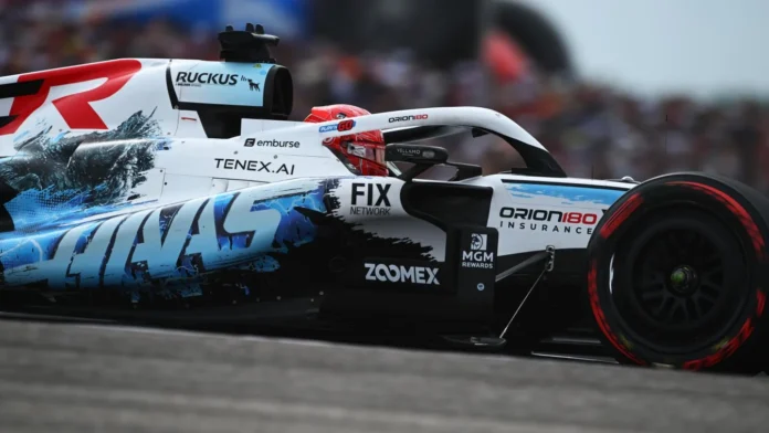 Mobil balap Haas Formula 1 berwarna putih biru hitam melaju di lintasan