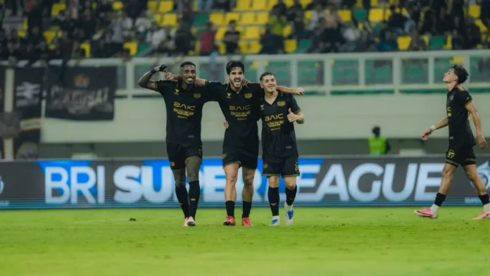 Sejumlah pemain berseragam hitam dengan aksen emas merayakan gol di lapangan sepak bola