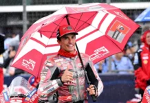 Marc Marquez Enggan Gunakan Pengaruh Media untuk Serang Rival Pembalap Ducati mengenakan perlengkapan balap merah memegang payung di area sirkuit dan mengacungkan jempol