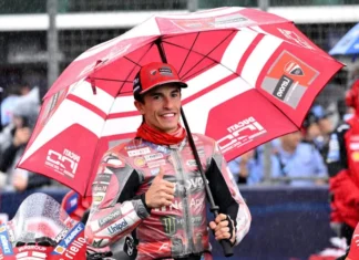 Marc Marquez Enggan Gunakan Pengaruh Media untuk Serang Rival Pembalap Ducati mengenakan perlengkapan balap merah memegang payung di area sirkuit dan mengacungkan jempol