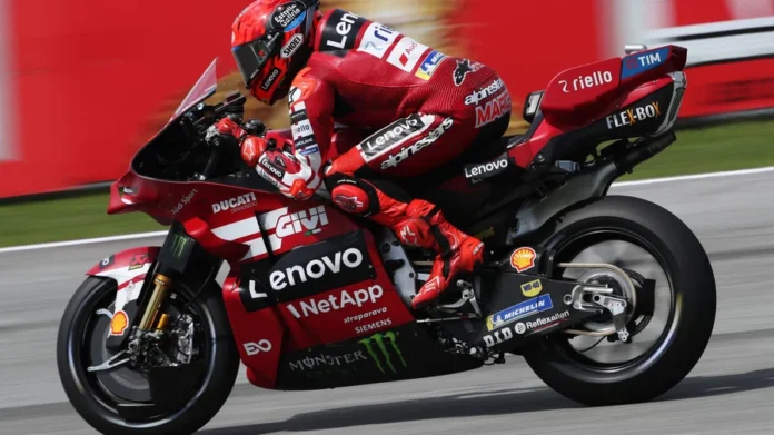 Marc Marquez dengan Motor Ducati Lenovo Pembalap mengenakan perlengkapan balap merah Ducati Lenovo melaju di lintasan dengan motor balap merah.