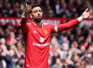 AC Milan Pantau Bruno Fernandes, Gaji Tinggi Jadi Kendala Pemain Manchester United berseragam merah mengangkat kedua tangan di lapangan