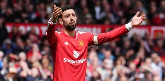 AC Milan Pantau Bruno Fernandes, Gaji Tinggi Jadi Kendala Pemain Manchester United berseragam merah mengangkat kedua tangan di lapangan