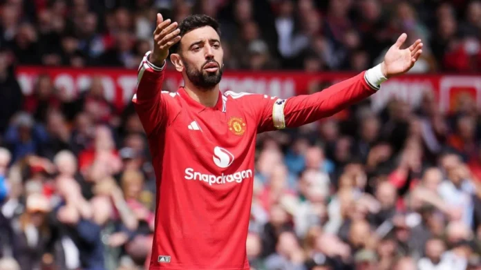 Pemain Manchester United berseragam merah mengangkat kedua tangan di lapangan