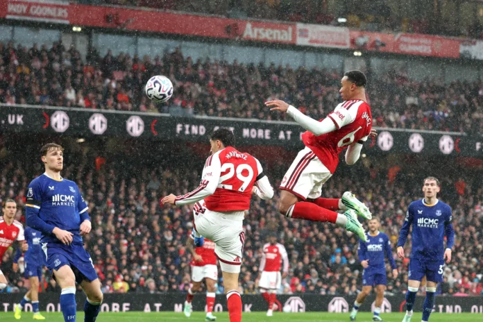 Dua pemain Arsenal melompat menyambut bola dalam pertandingan melawan Everton di Emirates Stadium.