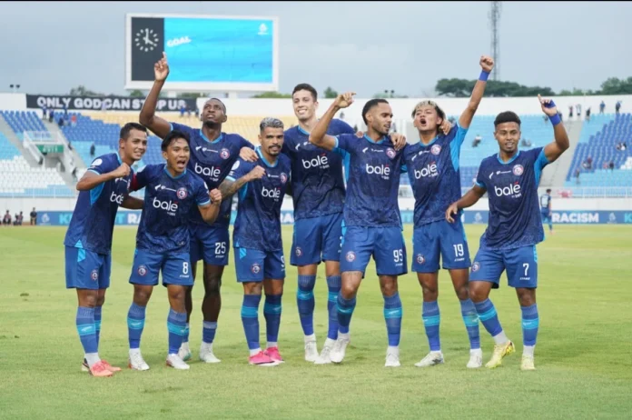 Sejumlah pemain Arema FC berpose bersama dan mengangkat tangan di lapangan